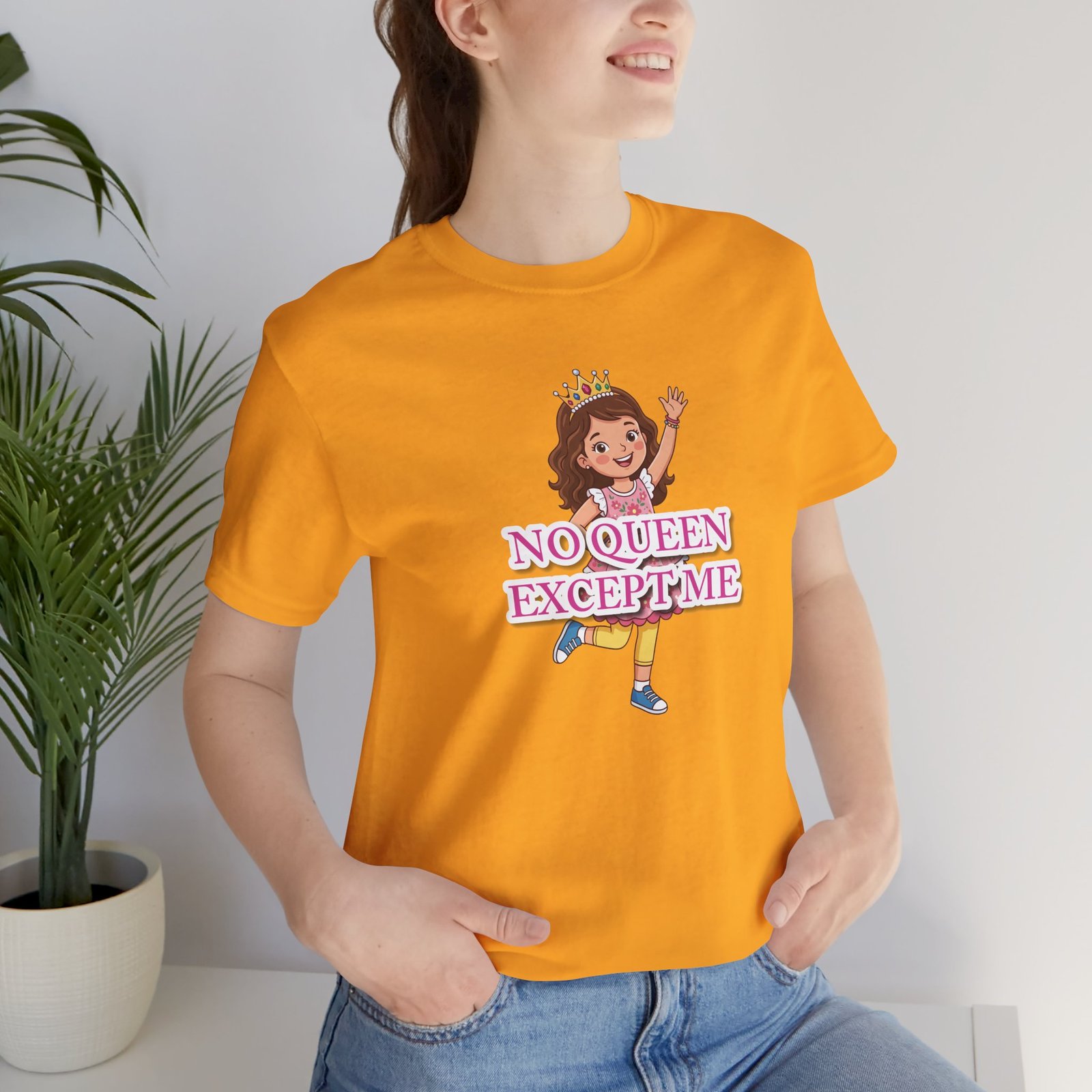 Girl wearing an orange 'No Queen Except Me' t-shirt featuring a whimsical illustration of a confident little queen.