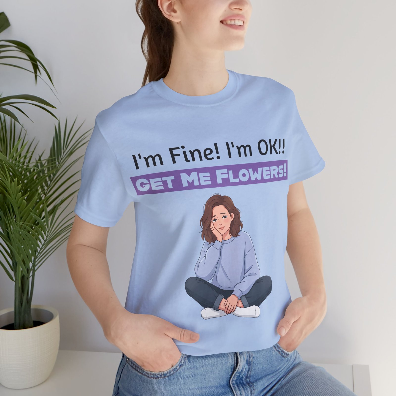 Light blue funny T-shirt featuring an illustration of a girl and text reading I'm Fine! I'm OK!! GET ME FLOWERS!