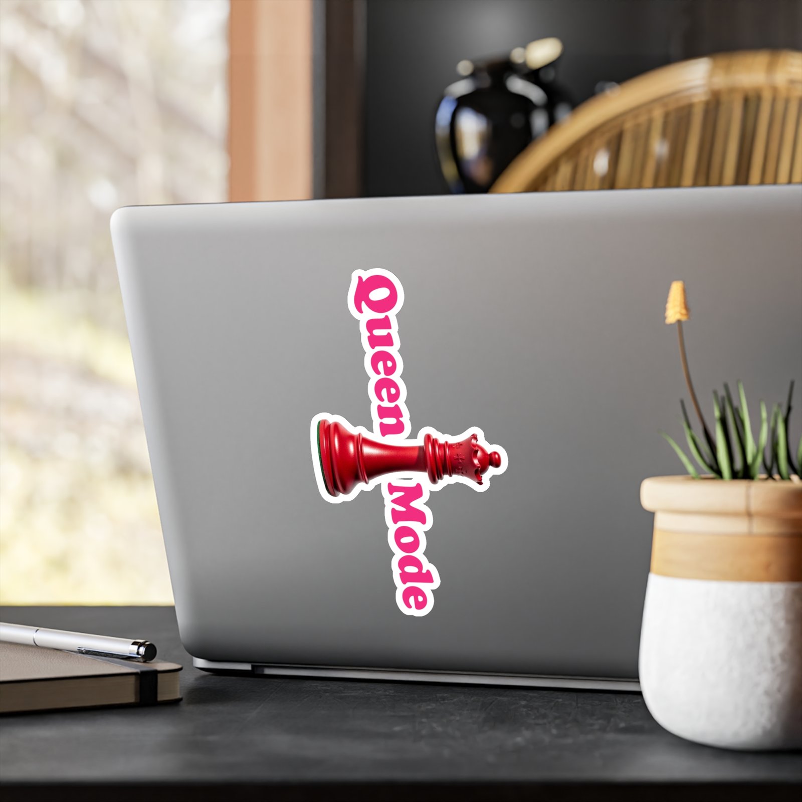 Queen Mode red chess queen sticker with pink vertical lettering on a grey laptop.