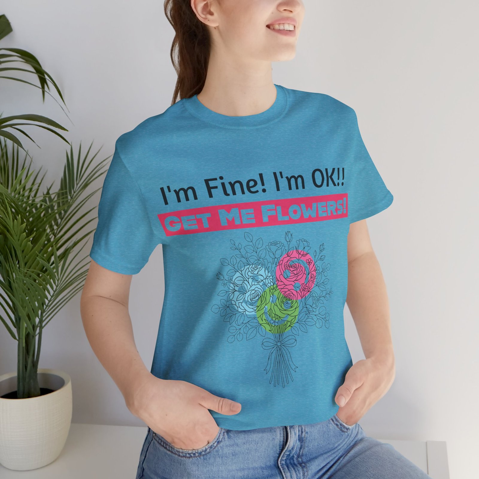 Woman wearing a blue t-shirt with 'I'm Fine! I'm OK!! Get Me Flowers!' text and a colorful floral bouquet design.