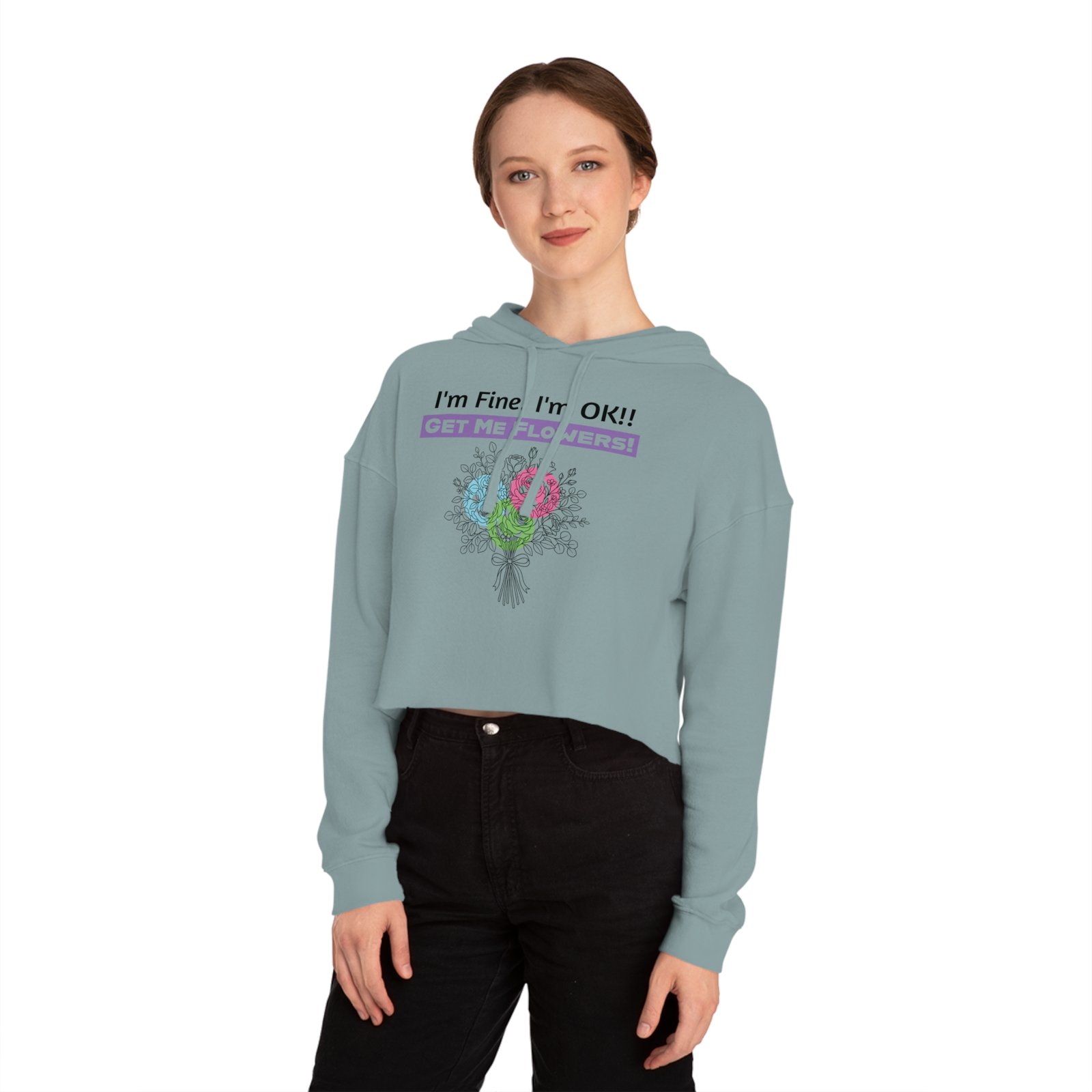 Woman wearing a light blue cropped hoodie with colorful flower graphic and "I'm Fine! I'm OK!! GET ME FLOWERS!" text.
