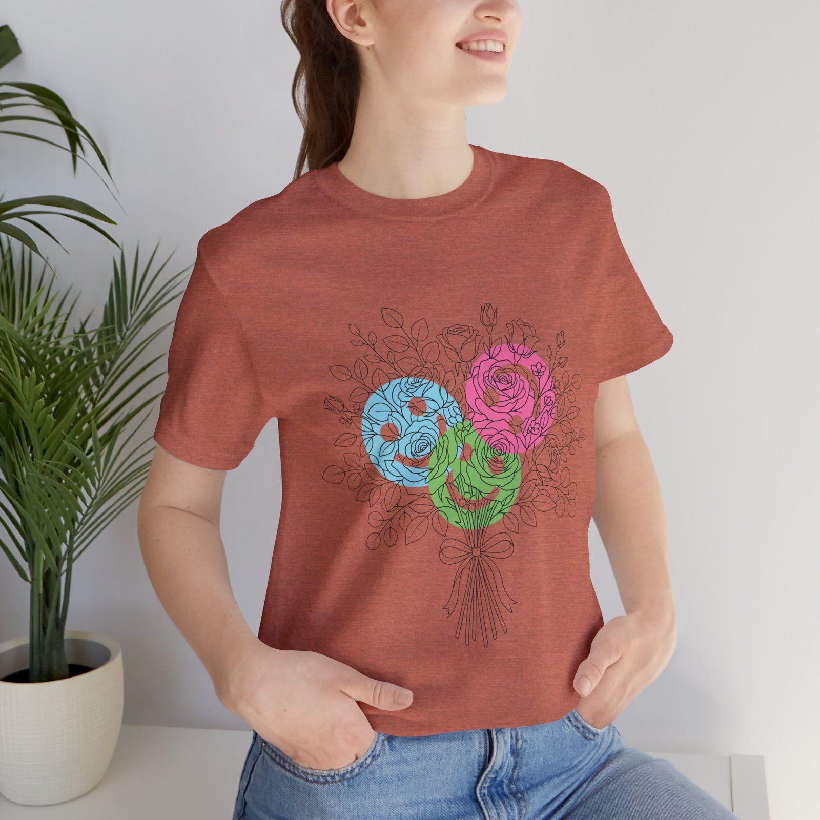 Woman wearing a rust-colored t-shirt featuring a colorful hand-drawn bouquet of teal, magenta, and lime flowers.