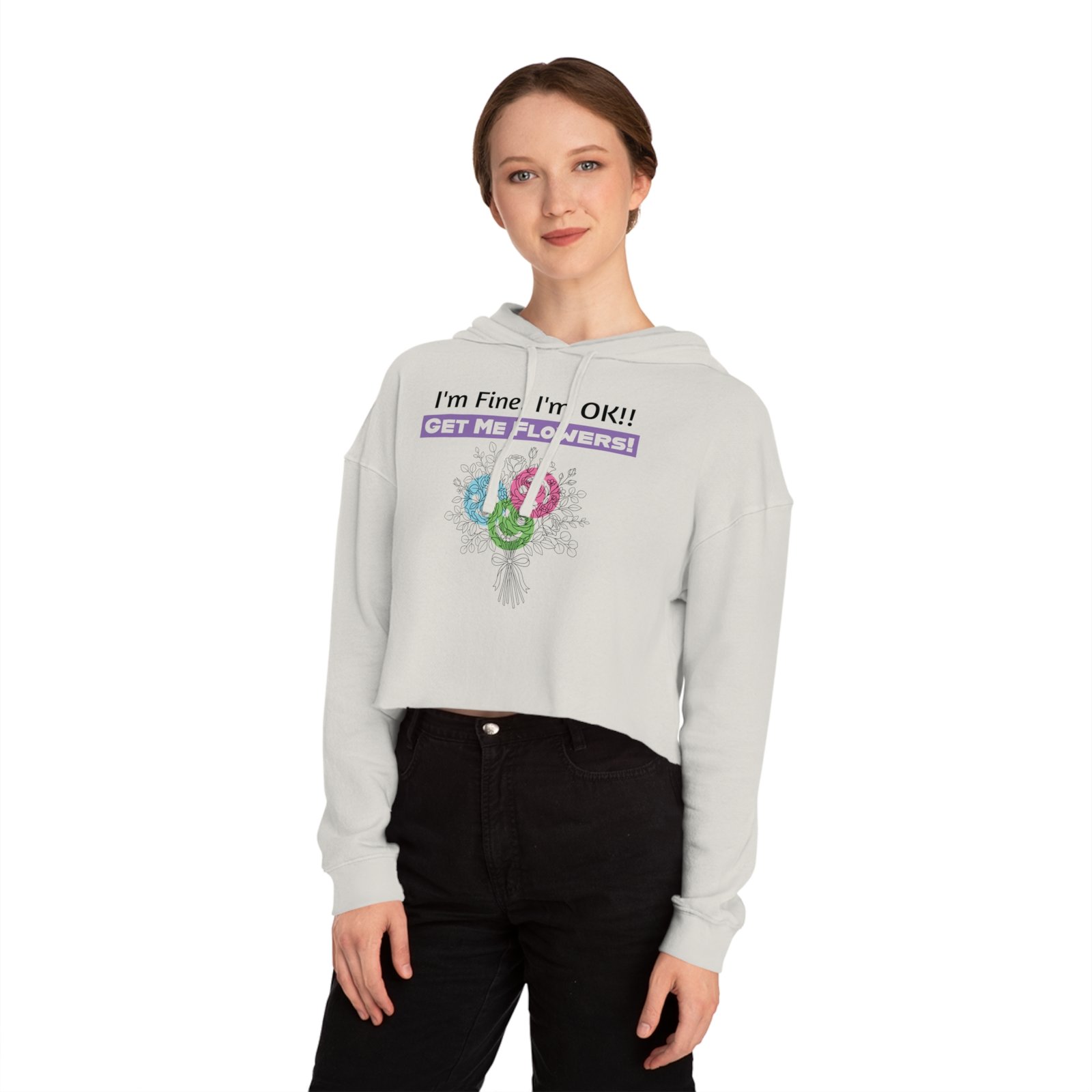 Woman wearing a white cropped hoodie with "I'm Fine! I'm OK!! Get Me Flowers!" floral graphic and a purple accent.