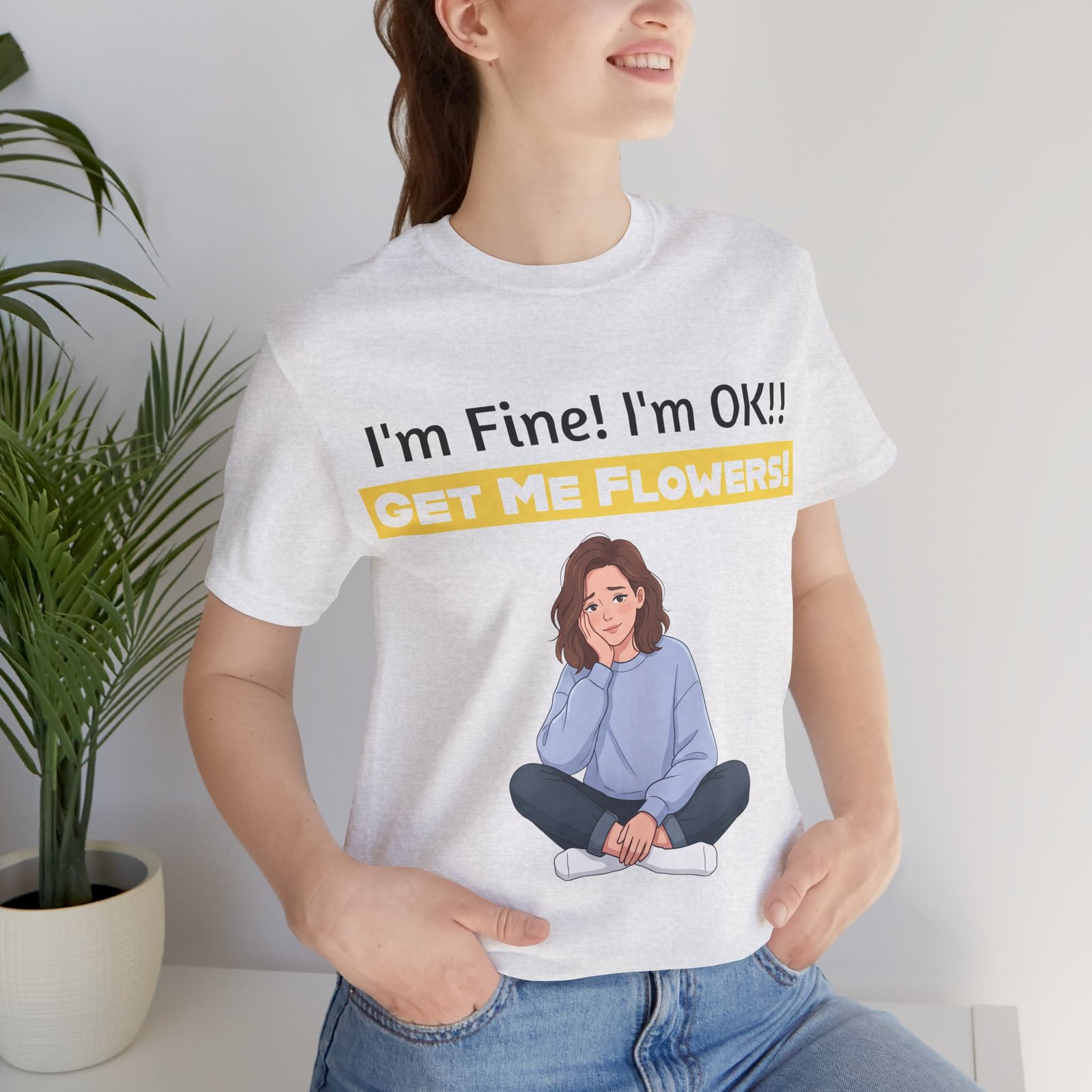 Woman wearing a white t-shirt with an illustration of a girl and the funny text "I'm Fine! I'm OK!! GET ME FLOWERS!"