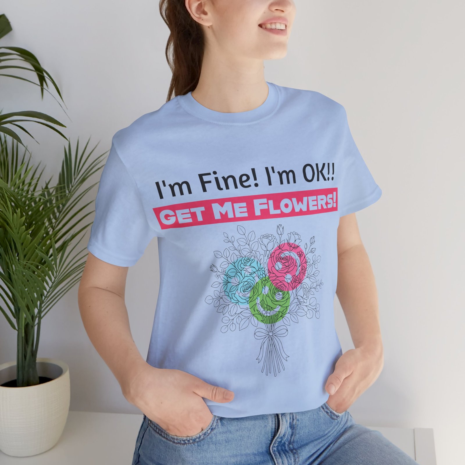 Woman wearing light blue t-shirt with 'I'm Fine! I'm OK!! Get Me Flowers!' text and colorful flower bouquet graphic.